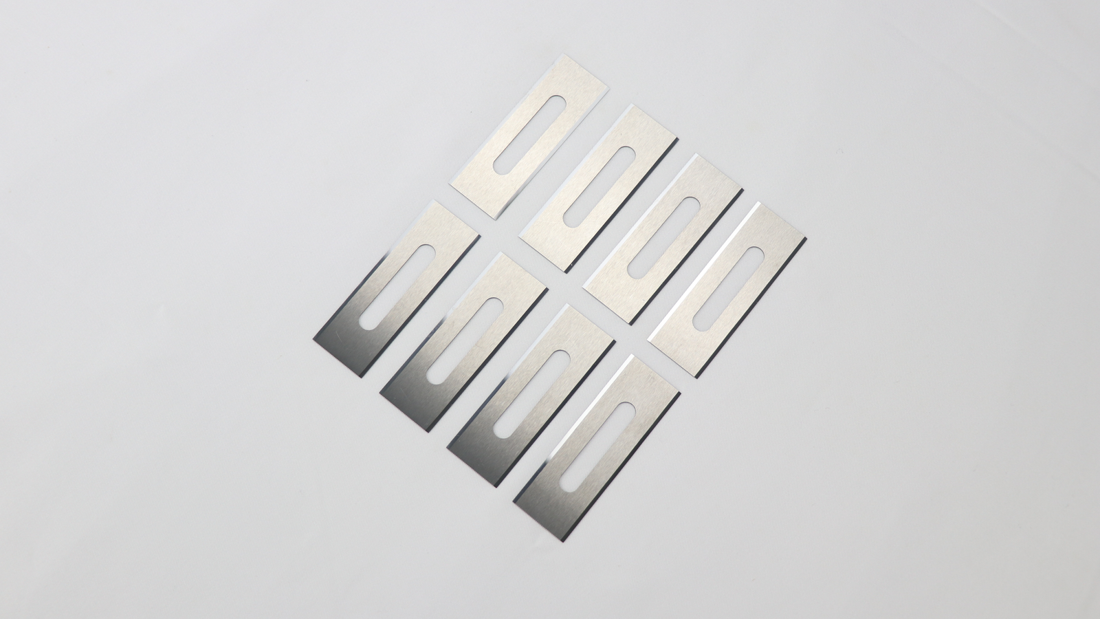 A close-up comparison of a slotted razor blade and a three-hole blade for the chemical fiber industry