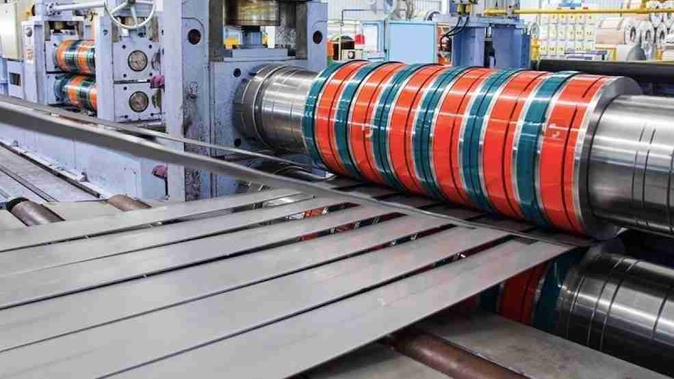 A close-up of an industrial blade slitting a roll of sheet metal