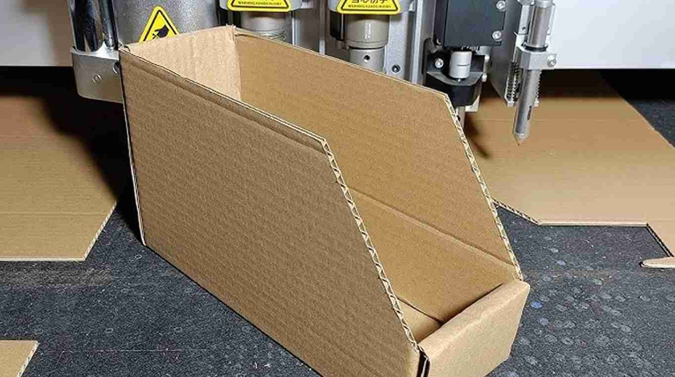 A CNC machine creating a crease line on a cardboard box prototype.