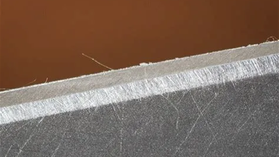 Close-up of a clean cut on material vs a rough cut with burrs