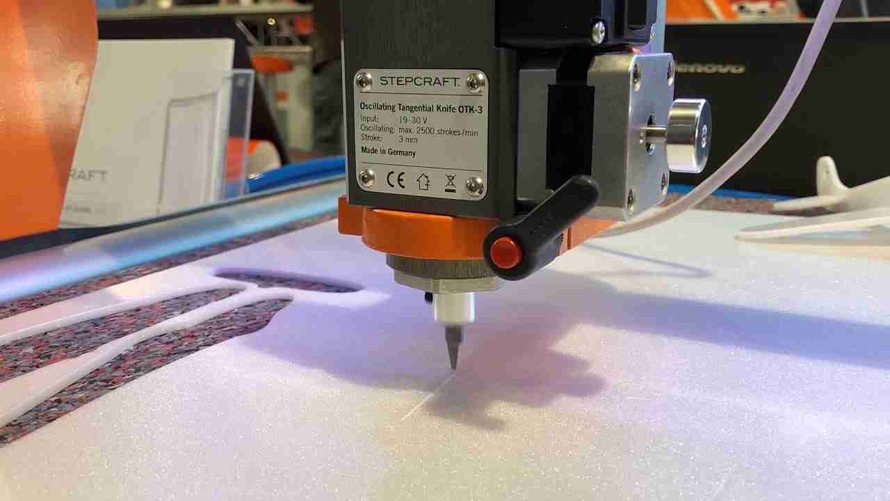 A CNC oscillating knife blade in action, cutting a detailed pattern into foam.