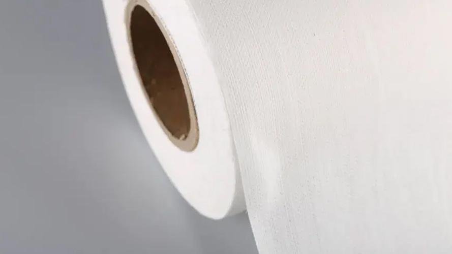An industrial machine cleanly cutting rolls of white non-woven fabric