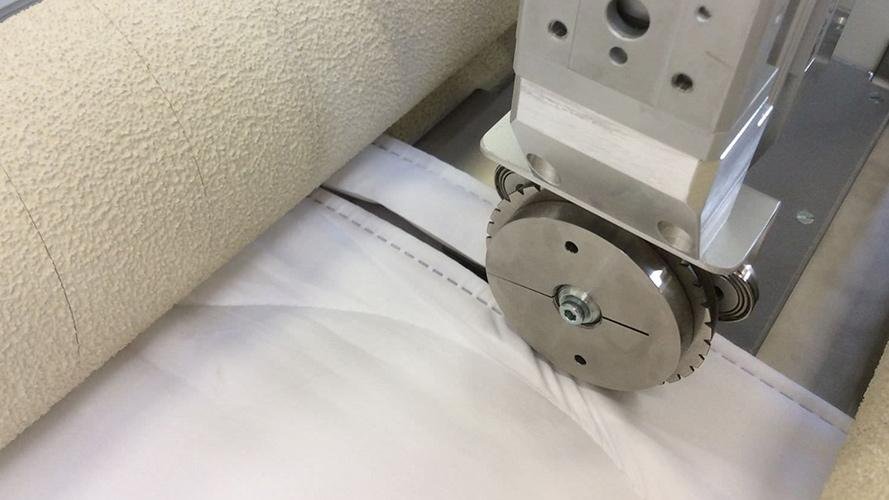 A close-up shot of a high-speed steel blade cleanly slitting a thin plastic film.