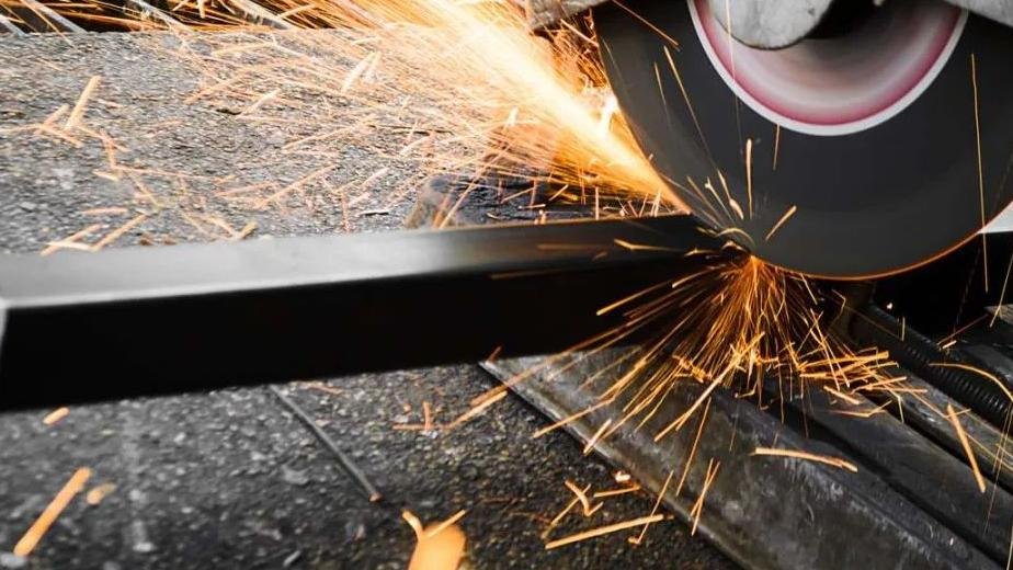 A close-up of a tungsten carbide blade cutting through metal, showing sparks