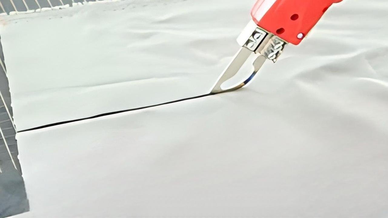 A hot knife sealing the edge of a synthetic fabric as it cuts