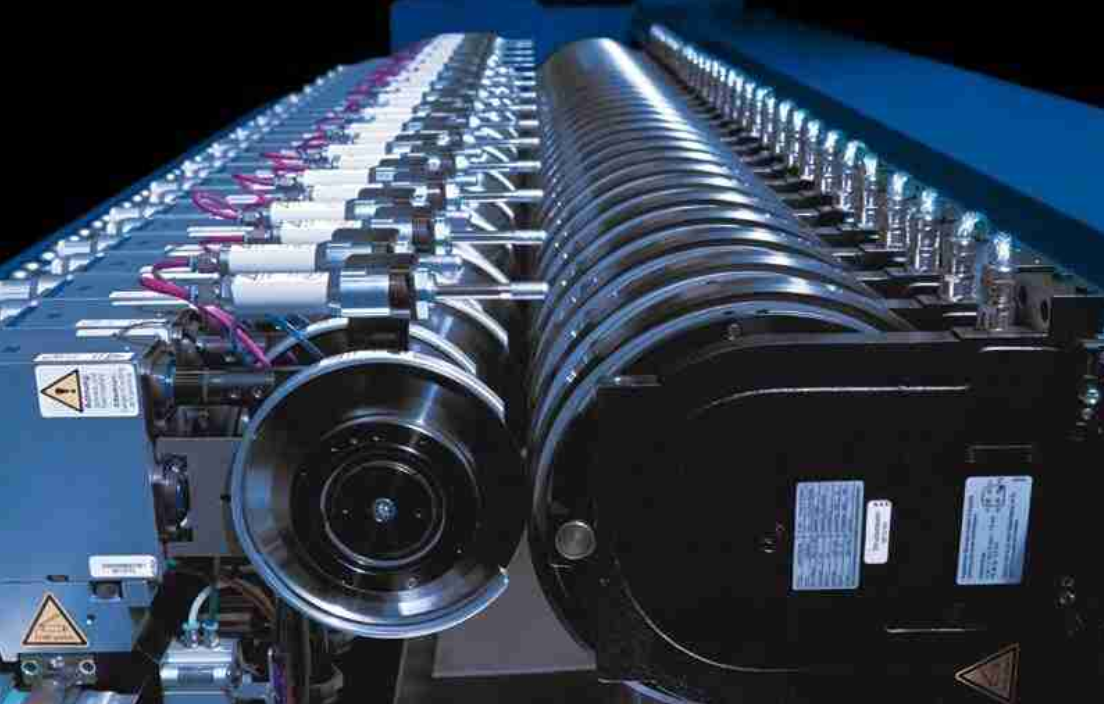 An industrial cutting machine in operation, showing the material feed and blade assembly