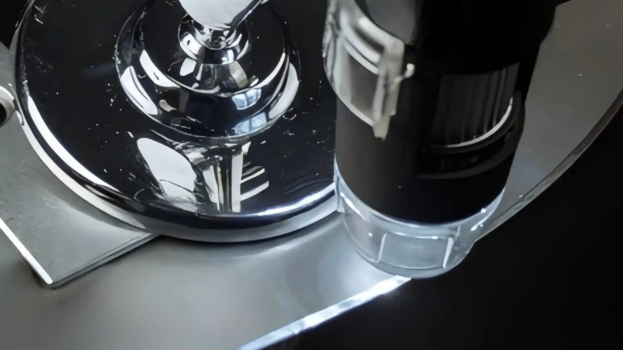 An inspector examining a machine blade with a magnifying glass.