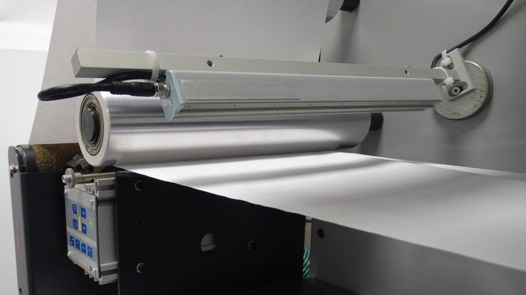 A clean, well-lit manufacturing environment with a machine featuring air cooling and static elimination bars.