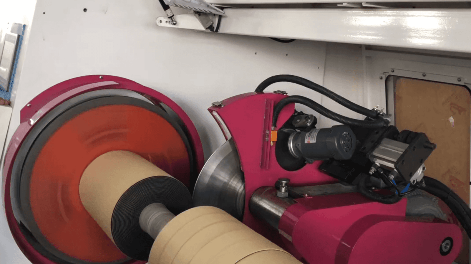 A close-up of an industrial blade cutting through a roll of tape