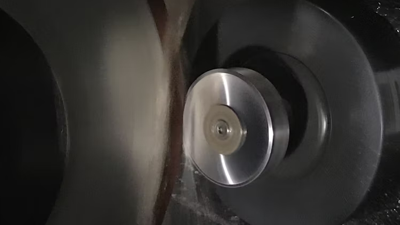 A close-up of a grinding wheel sharpening an industrial blade