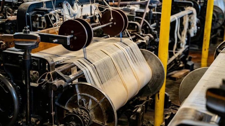 A vintage-style photo of an early industrial cutting machine in a textile factory