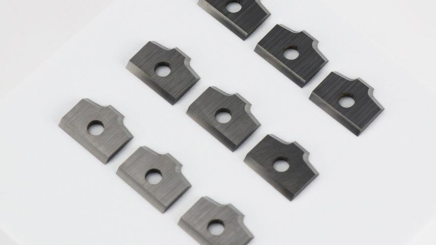An assortment of indexable industrial cutting blades with different coatings and shapes.