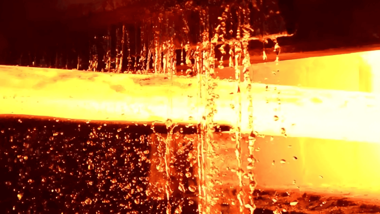 A glowing hot industrial blade being moved by a robotic arm in a modern factory.